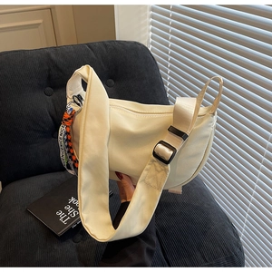 Detail of off-white crescent crossbody bag featuring an adjustable strap and printed ribbon