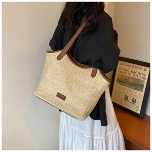 Detail of straw tote bag with brown leather straps shown on model in resort style