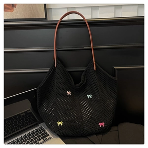 Close-up of black crochet tote bag featuring colorful bows and brown leather straps