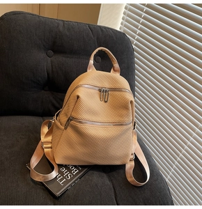 Detailed view of beige woven backpack texture and metal zipper pockets on a plush sofa