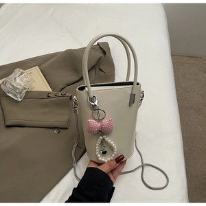 Detail der cremefarbenen Beuteltasche mit Perlenanhänger auf weißem Bettzeug