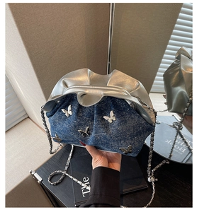 Detail of denim and silver leather pleated cloud bag with metallic butterfly accents