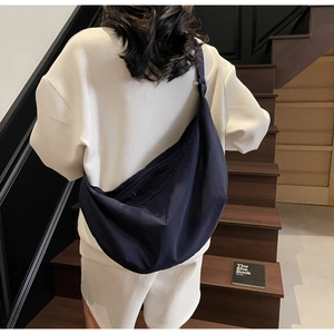 Detail of a large navy nylon crescent bag showing the adjustable strap and back view