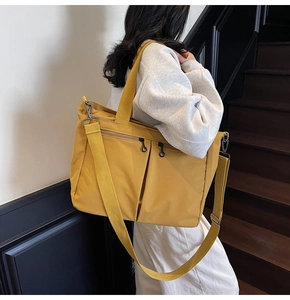 Detail of bright yellow tote bag with reinforced handles and large zipper pockets