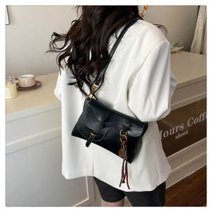 Detail of black saddle bag with contrast white stitching and gold tassel hardware