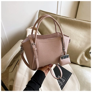 Detail of light pink lychee leather handbag with dual handles and mini charm