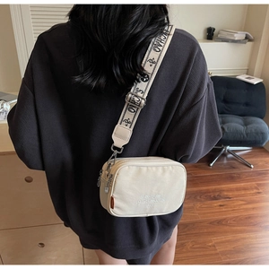 Modern canvas camera bag with wide jacquard strap and dual zippers shown in lifestyle setting