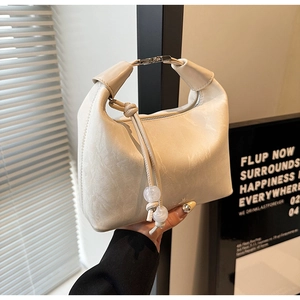 Detail der cremeweißen Leder-Tasche mit plissiertem Griff und silberner Metallschnalle
