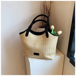 Detail of straw woven tote bag with black handles and elegant decorative white tulips