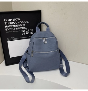 Close-up of misty blue nylon backpack featuring silver hardware and dual zipper pockets