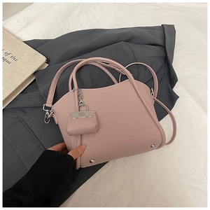 Detail of pink lychee leather handbag featuring metal studs and mini pouch charm