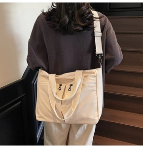 Close-up of beige canvas tote bag showing large capacity pockets and wide shoulder strap