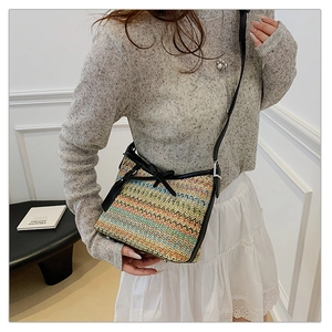 Close-up of colorful zigzag woven handbag featuring black bow detail and slim shoulder strap