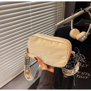 Detail of off-white canvas camera bag with wide SJCHAO strap and slogan embroidery