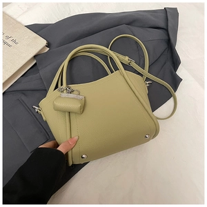 Detail of light olive green pebbled leather bucket bag with a mini coin purse charm