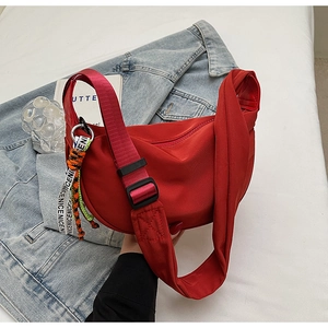 Detail of red nylon crescent bag featuring a contrast 'NICE' ribbon and adjustable strap