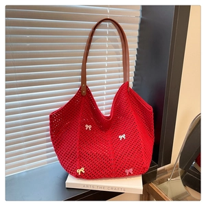 Close-up of red crochet tote bag with colorful bows and brown leather handles