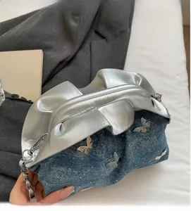 Detail of silver metallic and denim patchwork bucket bag with butterfly metal accents