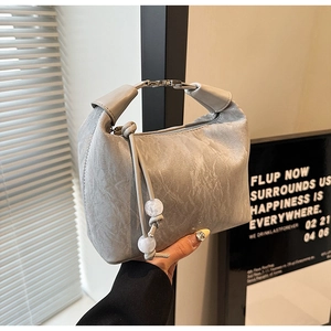 Detail der grauen Faltenledertasche mit Metallgriff und Perlenfransen-Verzierung
