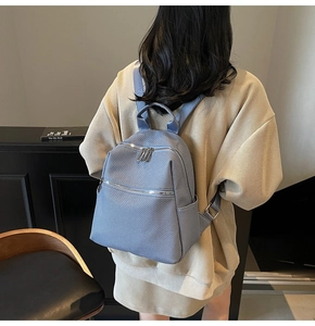 Detail view of the blue nylon backpack showing twill texture and silver zippers on a model