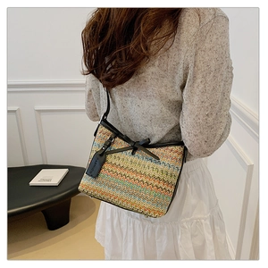 Detail of colorful woven shoulder bag with black leather bow and fashion tag on model