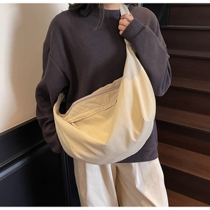 Close-up of a large cream canvas crescent bag showing the wide strap and soft drape