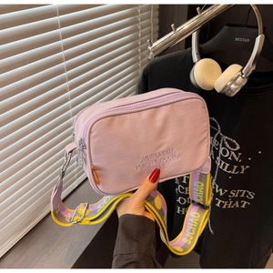 Close-up of lavender canvas camera bag with wide colorful strap and modern embroidery