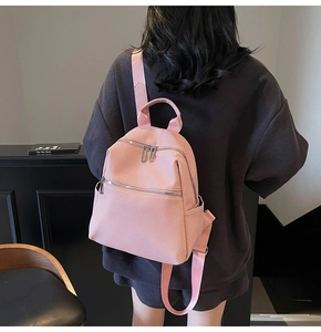 Detailed close-up of pink mini backpack with woven texture and dual zipper closure