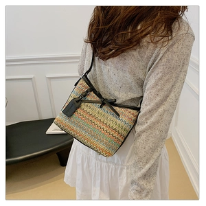 Detail of colorful zigzag woven bag with black leather bow and fashion tag on shoulder strap