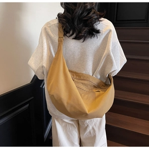 Rear view of khaki canvas crescent crossbody bag showing its large capacity and drape