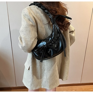Borsa a mezzaluna in vernice nera con fiocco indossata da una modella elegante