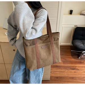 Sac fourre-tout en toile marron porté à l'épaule, fait de tissu épais de style vintage