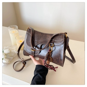 Detail of vintage brown saddle bag with contrast stitching and tassel pendant