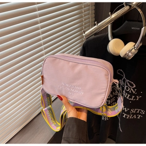 Detail of purple nylon crossbody bag with New Dreams embroidery and wide colorful strap