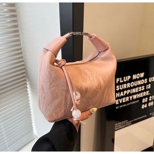 Detailaufnahme der rosa Tasche mit Faltenstruktur und runden Dekoelementen am Griff