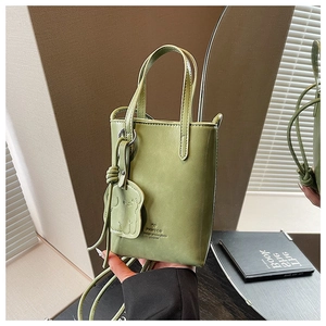 Detail of green mini bucket bag with animal charm and embossed logo on smooth leather