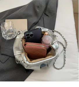 Silver pleated bucket bag on a grey suit showing its large storage capacity for cosmetics