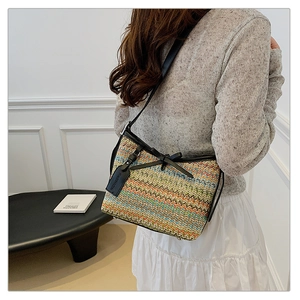Detail of colorful woven shoulder bag featuring leather trim and fashion pendant