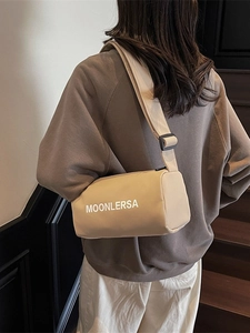 Beige cylindrical crossbody bag with wide strap and Moonlersa print worn by model