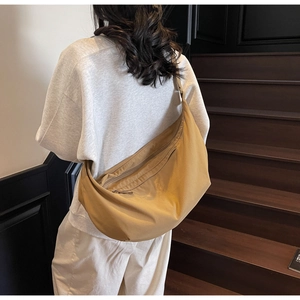 Detail of camel crescent crossbody bag showing large capacity and hidden zipper pocket