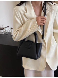 Modern black litchi pattern bucket bag with round buckle shown in a lifestyle setting