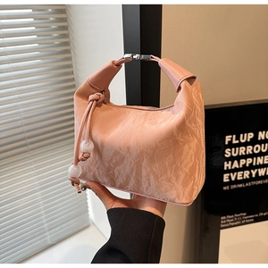 Detail der rosa Knotentasche mit plissiertem Stoff und dekorativem Perlenanhänger