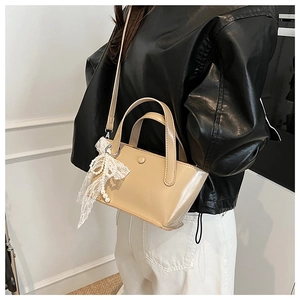 Dettaglio mini borsa tote beige con fiocco di pizzo e ciondolo di perle a tracolla