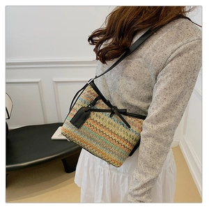 Detail of colorful woven shoulder bag with black leather trim and bow decoration
