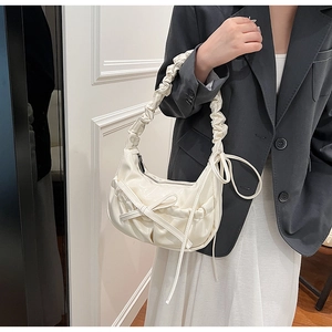 Detail of cream pleated crossbody bag with ribbon bow and soft cloud shoulder strap