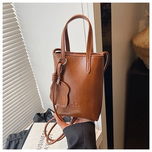 Detailed close-up of brown mini bucket bag featuring bear charm and FANTOR logo