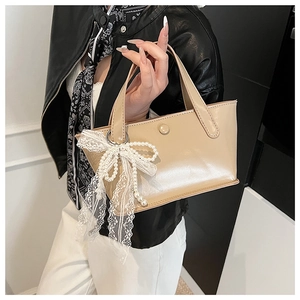 Dettaglio della borsa a secchiello beige lucido con fiocco in pizzo e perle