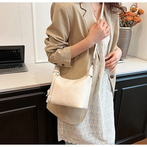 Detail der cremeweißen Hobo-Tasche aus Leder mit Seitenknoten und silbernem Reißverschluss