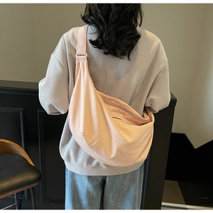 Back view of a model wearing the light pink minimalist crossbody dumpling bag