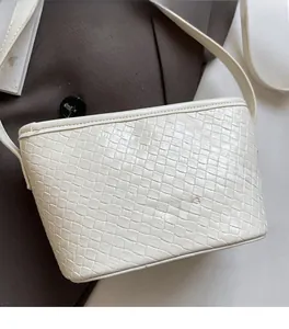 Macro shot of white woven texture and brand logo embossing on the minimalist bucket bag